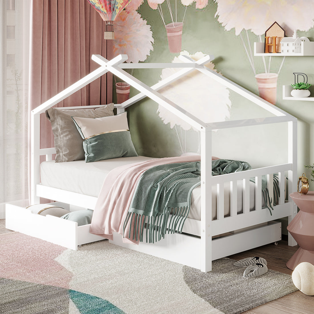 Tucker Solid Pine Timber Kids Bed with Drawers White, featuring a low house-frame design, coordinating pillows, teal throw, pink blanket, and partially open storage drawer revealing cushions, set against a playful mural backdrop.