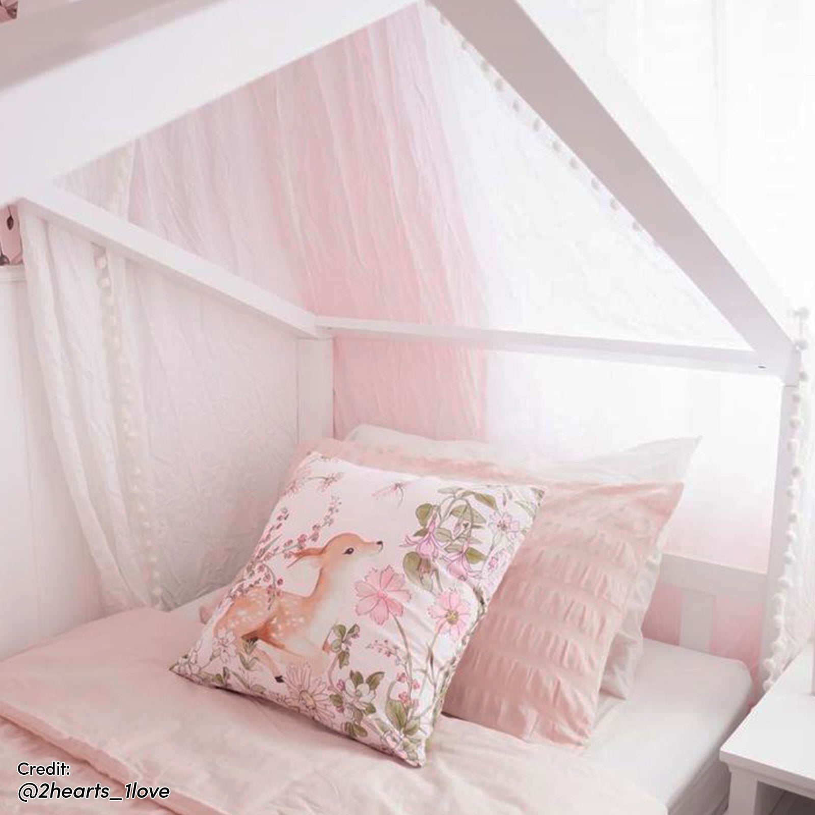 Tucker Solid Pine Timber Kids Bed with Drawers White features a house-shaped frame with blush-pink bedding, fawn-themed pillow, sheer drapes, and two storage drawers, creating a cozy, imaginative space.
