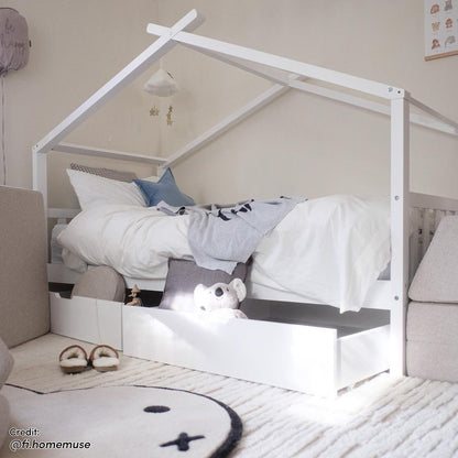 Tucker Solid Pine Timber Kids Bed with Drawers White features a house-frame design, white bedding, a pull-out drawer with a stuffed koala, and a cloud mobile, creating a cozy, imaginative space.