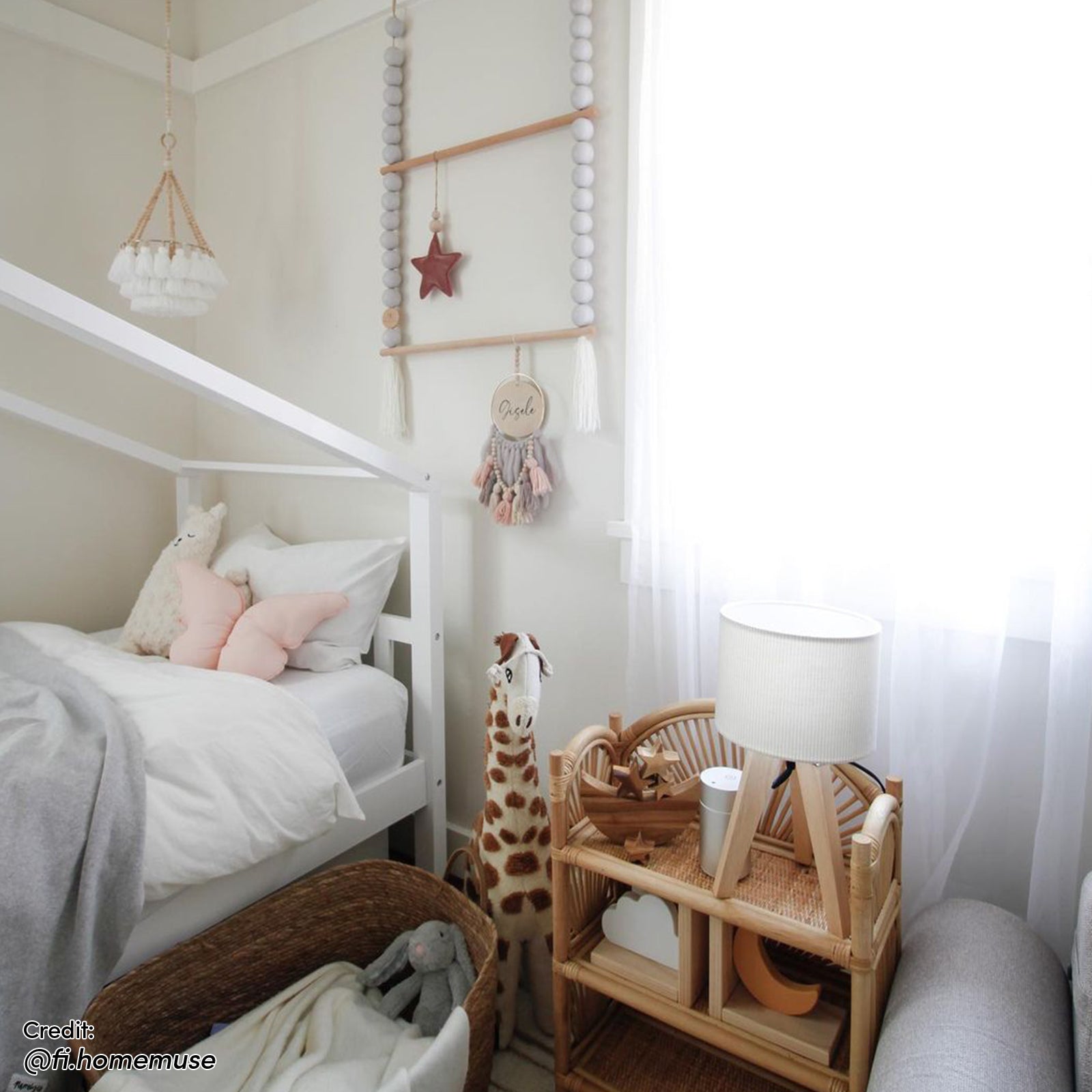 Tucker Solid Pine Timber Kids Bed with Drawers White, featuring a house-frame design, white linens, plush toys, and sheer curtains. Accompanied by a rattan side table with a lamp and decorative items.