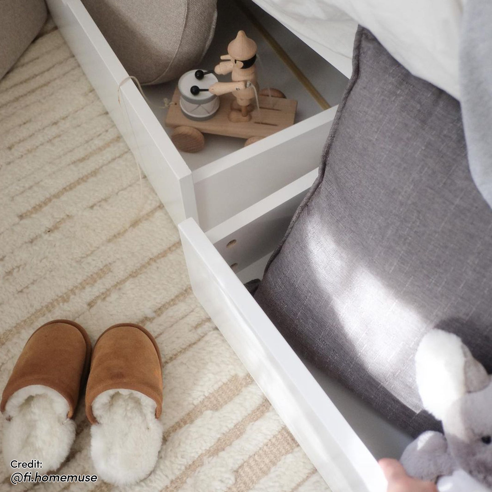 Tucker Solid Pine Timber Kids Bed with Drawers features two open storage drawers. A toy soldier and cushion with a plush elephant are visible, with brown slippers on a striped rug below.