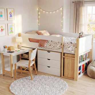 Yuri Storage Loft Bed with Pull Out Desk in White & Natural, featuring a raised bed with star-and-moon sheets, built-in drawers, open cubby, and a desk setup, ideal for organized, stylish spaces.