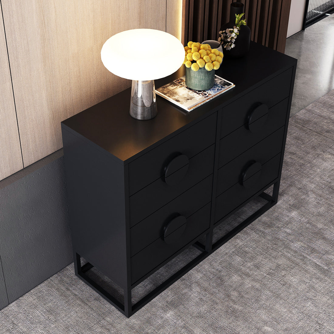 Abigail 120cm Lowboy Dresser with Drawers - Black, featuring six drawers with circular pulls, topped with a glowing mushroom lamp, books, and vases, set on a light gray carpet.