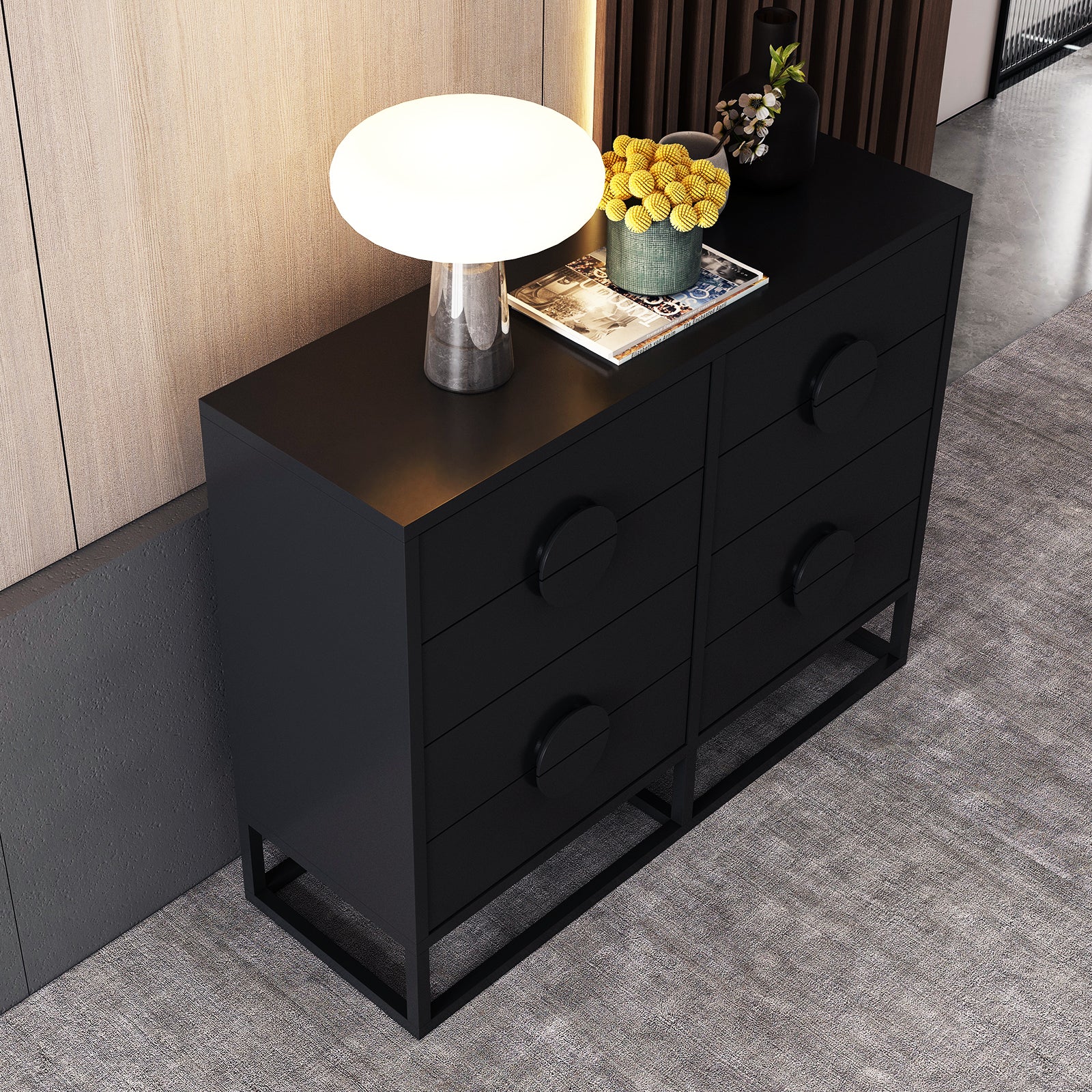 Abigail 120cm Lowboy Dresser with Drawers - Black, featuring six drawers with circular pulls, topped with a glowing mushroom lamp, books, and vases, set on a light gray carpet.