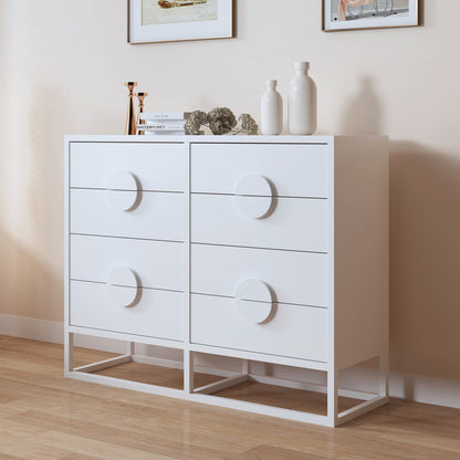 Abigail 120cm Lowboy Dresser with Drawers - White, featuring four drawers with circular pulls, topped with brass candlesticks, books, dried hydrangeas, vases, set against framed art on a beige wall.
