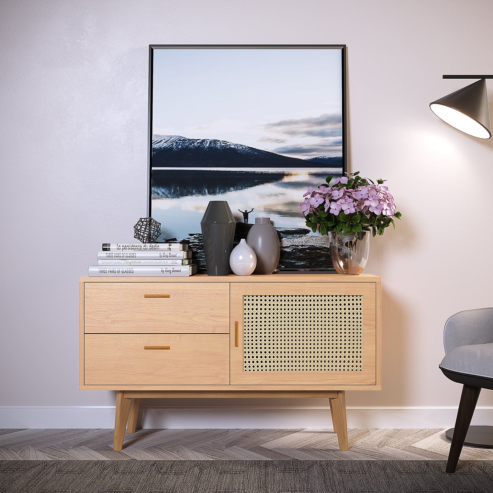 Bethany 120cm Sideboard with Drawers Natural against a pale wall, featuring two drawers and a cane-fronted cabinet, topped with decorative books, vases, and pink hydrangeas, next to a lit floor lamp.
