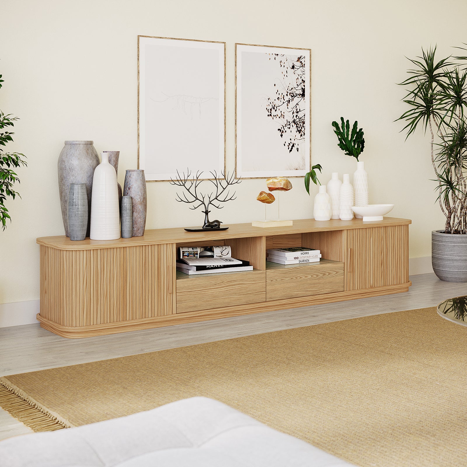 Eddie 200cm Hardwood Oak TV Entertainment Unit in Natural, showcasing open compartments with books, and adorned with ceramic vases, metal sculptures, framed art above, and flanked by potted plants.