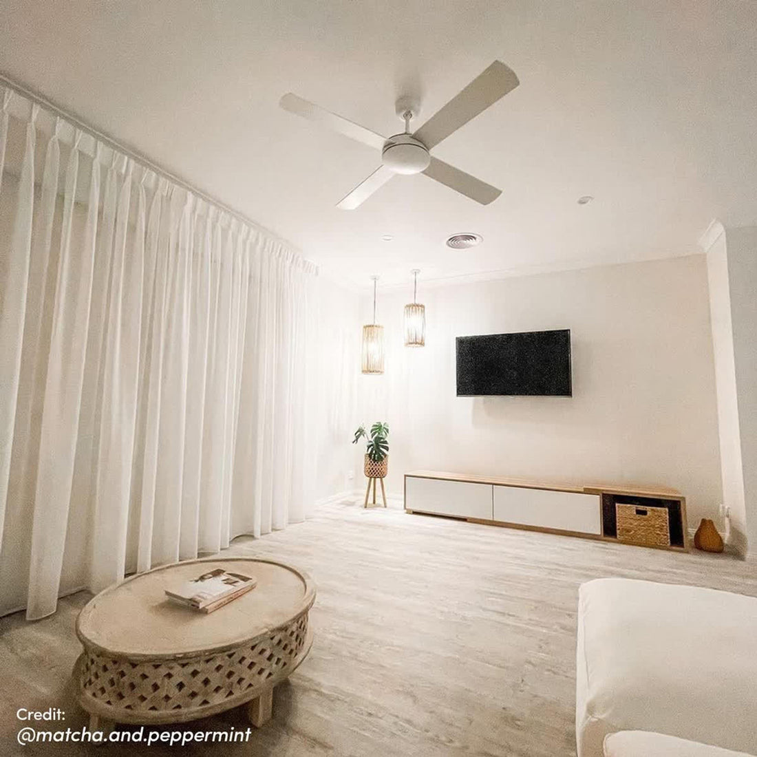 Eloise Entertainment Unit with Shelves - White, featuring open shelves and push-to-open doors, neatly arranged in a modern living room setting with a nearby ceiling fan and accent decor.