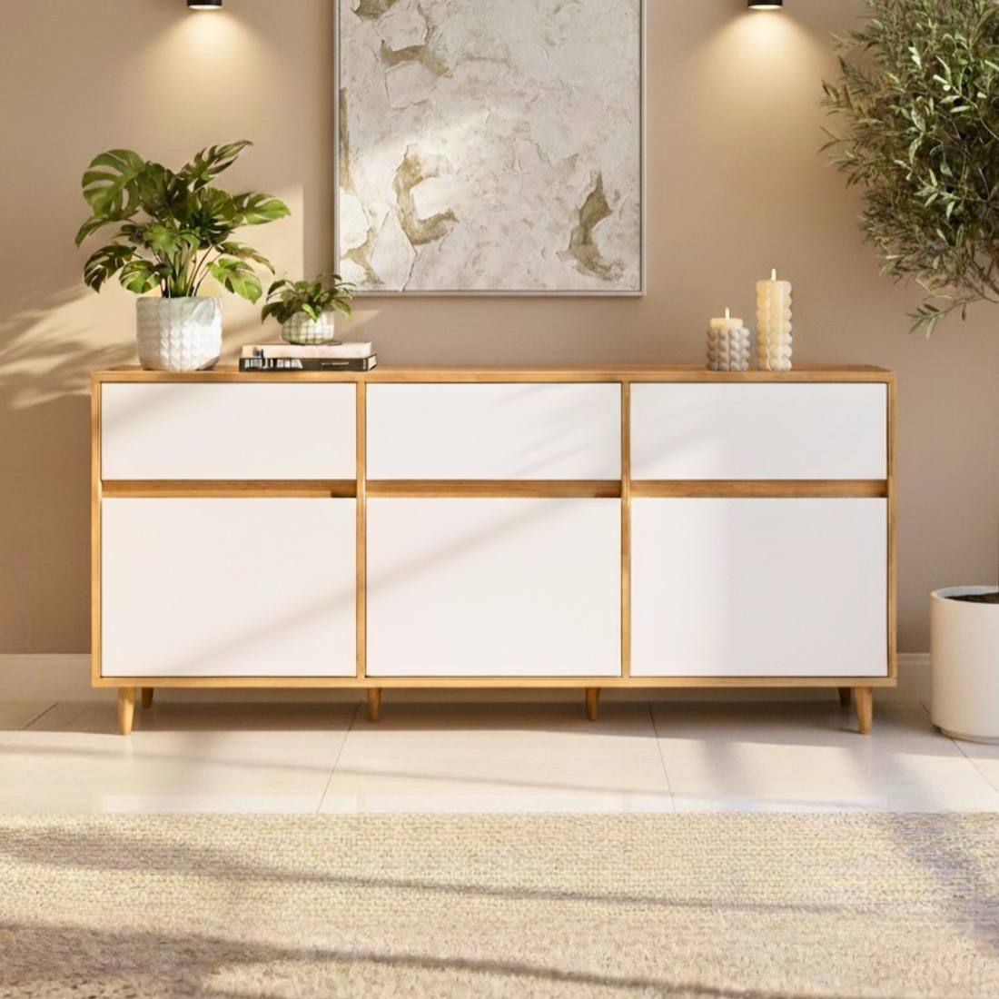 Ezra 6-Door Storage Buffet Sideboard in Natural & White with mid-century design, light wood frame, six white laminate drawers, topped with a tropical plant, books, candles, and abstract painting above.