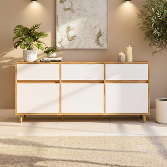Ezra 6-Door Storage Buffet Sideboard in Natural & White with mid-century design, light wood frame, six white laminate drawers, topped with a tropical plant, books, candles, and abstract painting above.