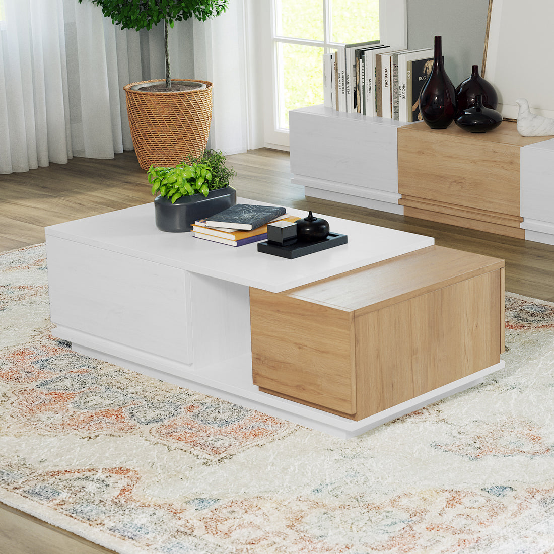 Freda 120cm Coffee Table with Storage in White & Natural, featuring a white top, warm wood accents, black planter, books, and a black tray, set on a patterned cream rug.