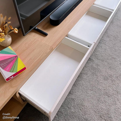 Galya Extendable Storage TV Unit - Oak shown on gray carpet with a flat-screen TV, sound-bar, vase, and book on top; drawers partially open revealing empty interiors.