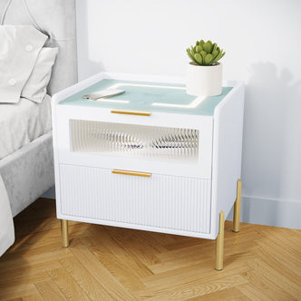 Gwen Smart Bedside Table with Wireless Charger in White, featuring two drawers, brass accents, and a built-in charging pad with LED strip. Topped with a potted succulent and smartphone.