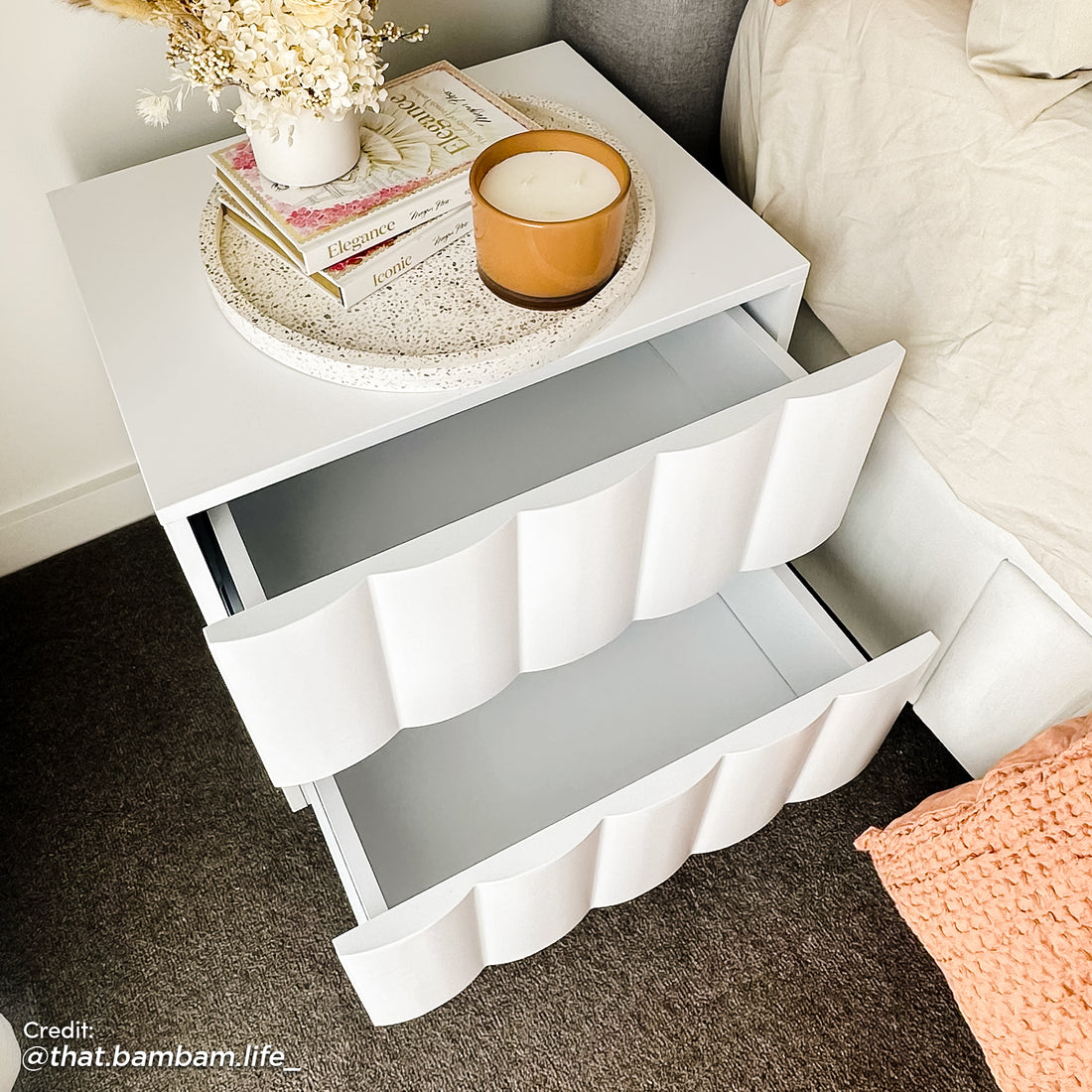 Top-down view of a white fluted bedside table with two open drawers, showing spacious storage and a wavy textured front design.