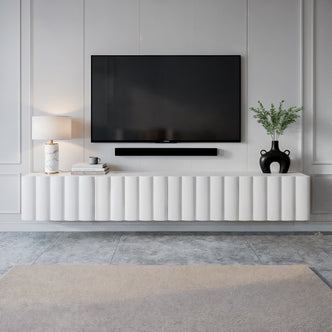 Hamish 200cm Fluted TV Storage Entertainment Unit in White, featuring a wave design, floats below a mounted TV, styled with a marble lamp, books, and a vase with greenery.