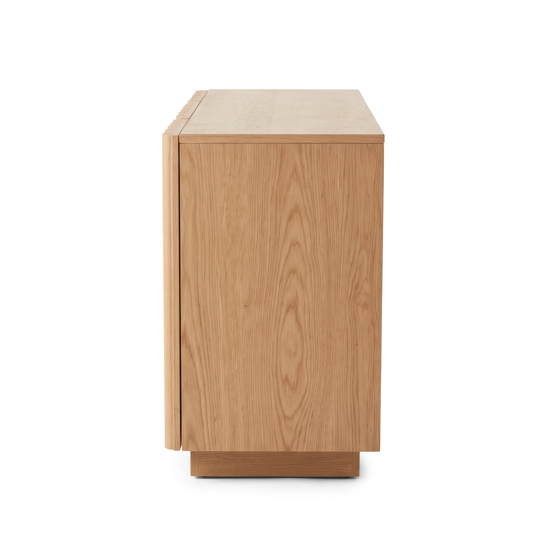 Side view of an oak sideboard highlighting the natural wood grain texture and vertical fluted door detailing against a plain white studio background.