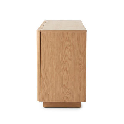 Side view of an oak sideboard highlighting the natural wood grain texture and vertical fluted door detailing against a plain white studio background.