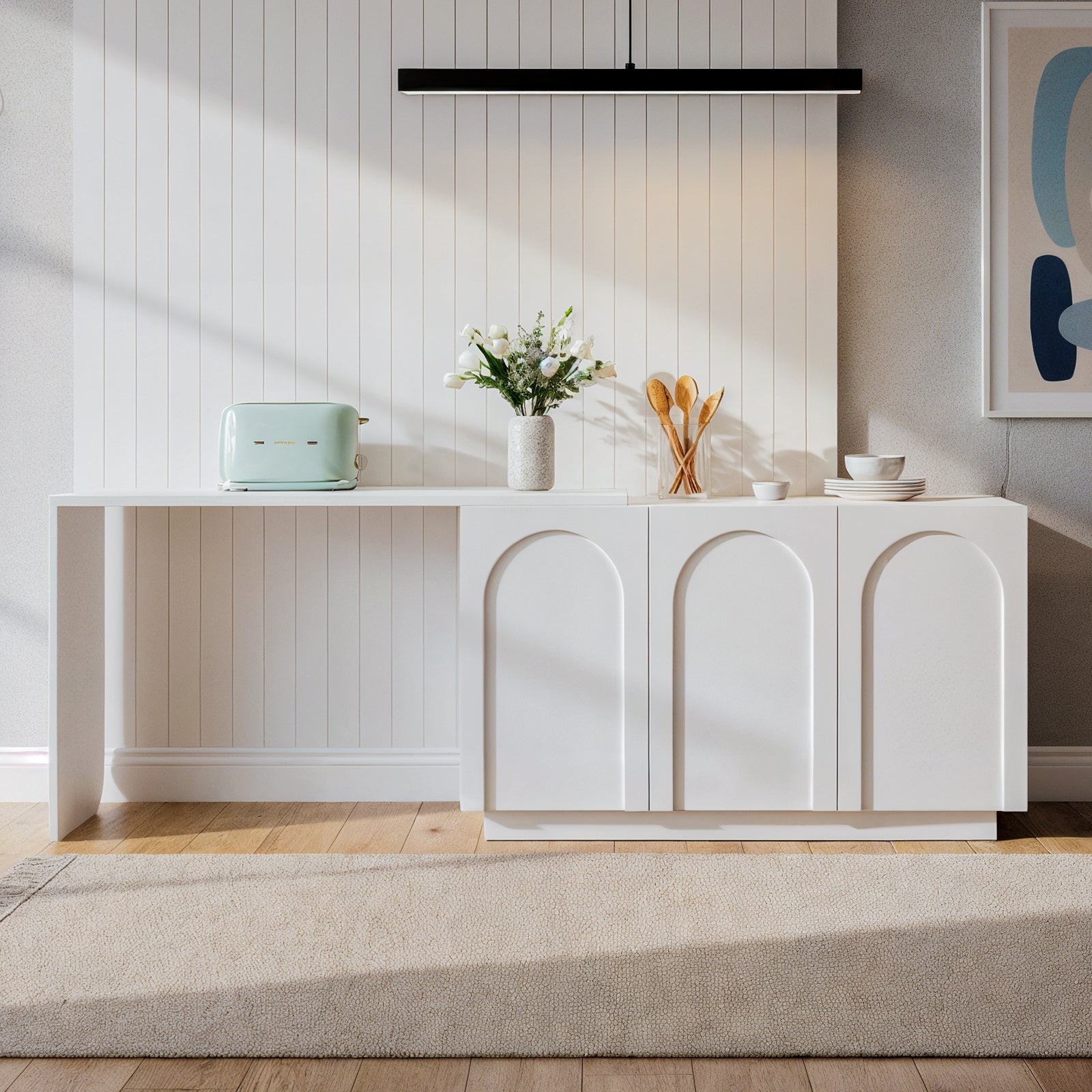 Hava 120cm Arched Extendable Sideboard Table in White with three arched doors, topped with a mint toaster, ceramic vase with flowers, glass container with spoons, and stacked dishes.