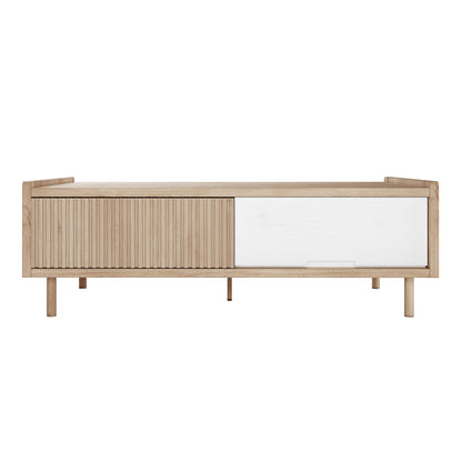 Hayden 130cm Fluted Coffee Table with Storage in Natural, featuring light-toned wood, sliding doors with vertical slats and a white panel, on short round legs, offering Scandinavian-inspired minimalist design.