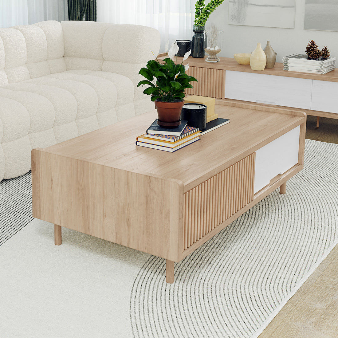 Hayden 130cm Coffee Table with Storage in Natural, featuring a rectangular wooden design on a light rug, adorned with a peace lily, books, and candles, in a minimalist living room setting.