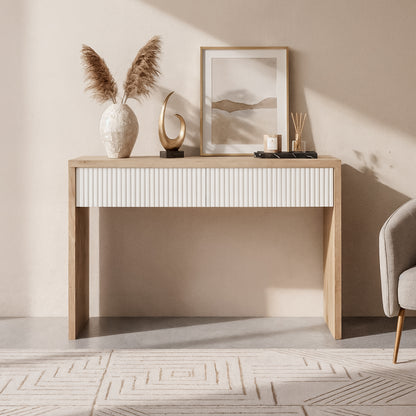 Hayden 120cm Fluted Hallway Table with Storage in Natural, featuring a white fluted-front drawer, pampas grass vase, abstract sculpture, tray with candle and diffusers; paired with a gray chair.