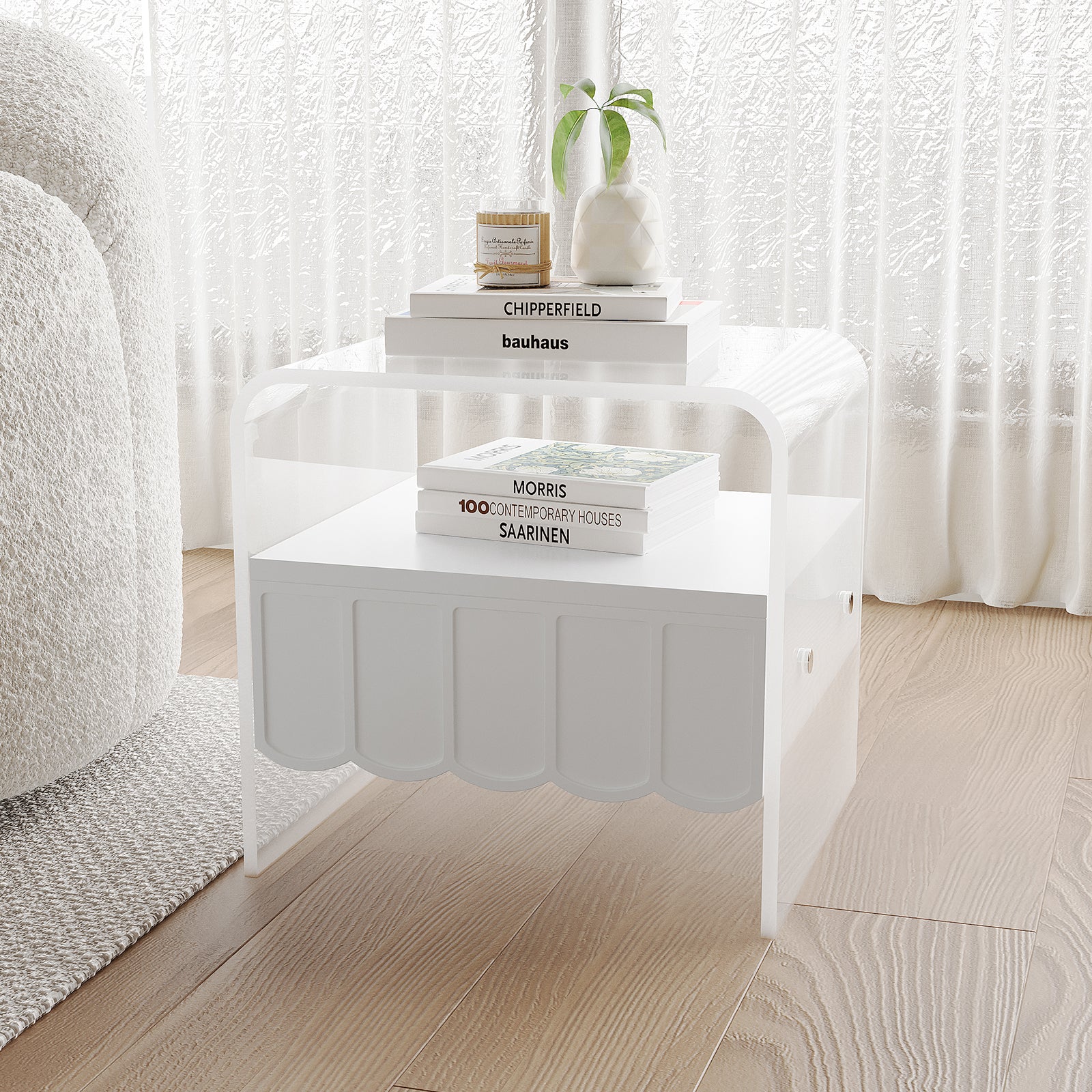 Magdalena 45cm Scalloped Acrylic Bedside Table in White with clear acrylic sides, a scalloped-front lower shelf, topped with a vase, candle, and stacked art books, next to a boucle sofa.