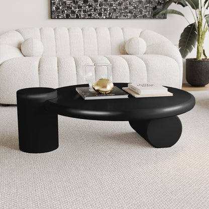 Nando 100cm Modern Round Coffee Table in Black featuring dual cylindrical supports, a glass tumbler, gold decorative orb, and books. Complements an off-white sofa and abstract artwork in a minimalist setting.