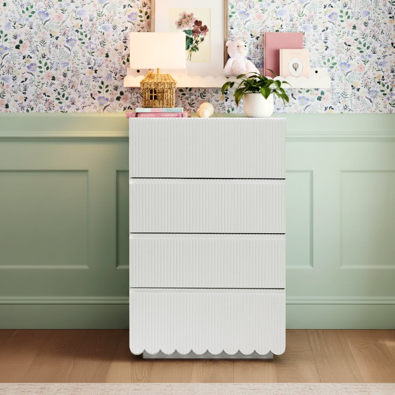 Nasrin 60cm Tallboy Dresser with Drawers in White, featuring four vertical-ribbed drawers and scalloped base, adorned with a wicker basket, books, decorative orb, potted plant, and lamp.