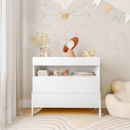 Quinta Tallboy Dresser with Drawers White featuring a low white cabinet with two deep drawers, an open shelf holding books and figurines, topped with decorative vases, a lamp, and a toy biplane.