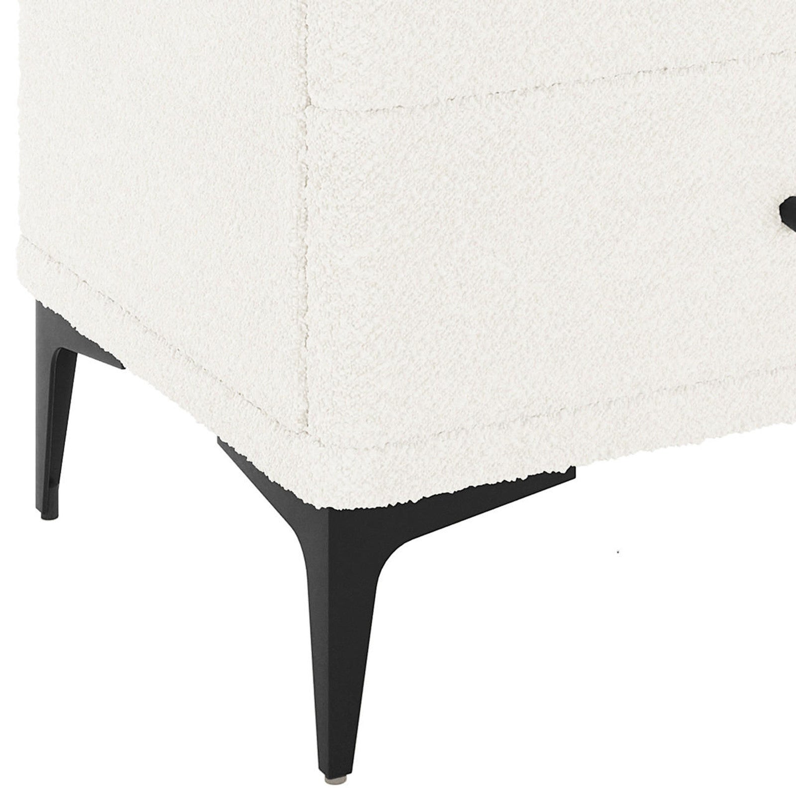 Shona Upholstered Boucle Bedside Table in Cream White, showcasing a corner with white textured fabric, supported by slim, tapered black metal legs, highlighting its modern elegance and functional design.