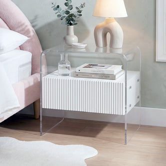 white acrylic nightstand styled next to bed in a bedroom