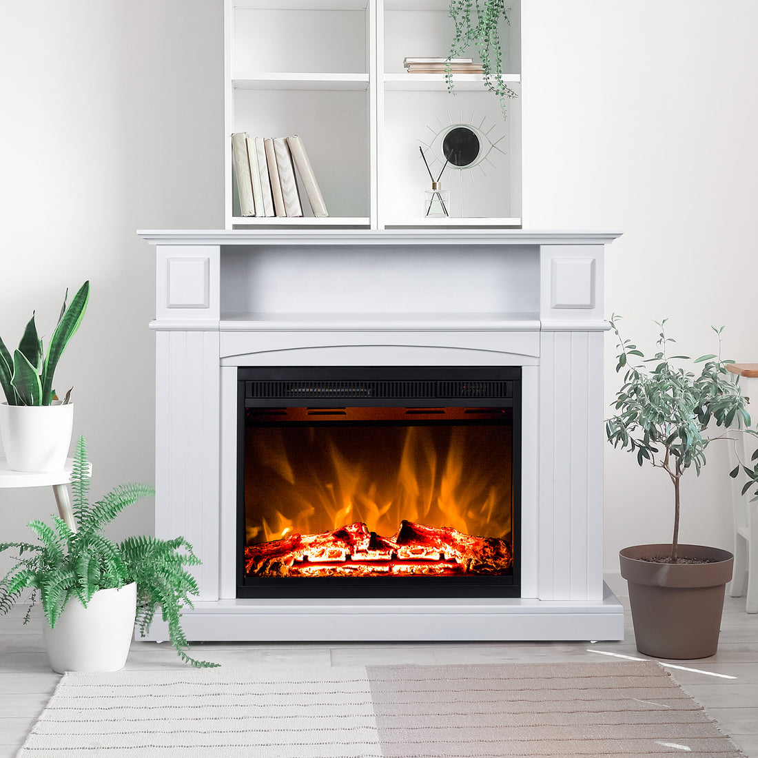 Banhi 1500W Electric Fireplace Heater with Mantel in White, featuring realistic LED flames, is flanked by potted plants and topped with books, a mirror, and a trailing plant on open shelves.