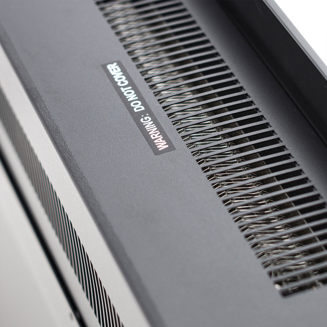 Close-up of the Dakota 60 Wall Mounted 1500W Electric Fireplace Heater showing its vented metal housing with slotted air grille, exposed heating coils, and “WARNING: DO NOT COVER” label.