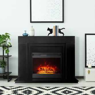 Oprah 1950W Free Standing Electric Mantel Fireplace in Black, featuring a sleek design with a minimalist mantel, decorative vases, books, and a bold geometric rug enhancing the cozy ambiance.