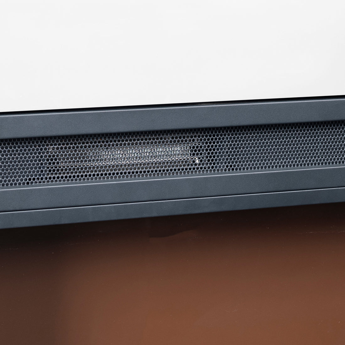 Oprah 1950W Free Standing Electric Mantel Fireplace in White, showcasing a white panel above a black honeycomb-style grille, set against a brown surface, highlighting its sleek, modern design.