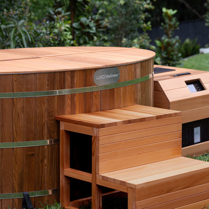 Denman 2 Person Outdoor Ice Bath with 1.5HP Chiller in Natural, featuring a wooden barrel-style design and matching entry bench, set outdoors with visible heater/control housing.