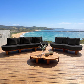 Outdoor patio sectional sofa set with coffee table on a wooden deck overlooking the ocean