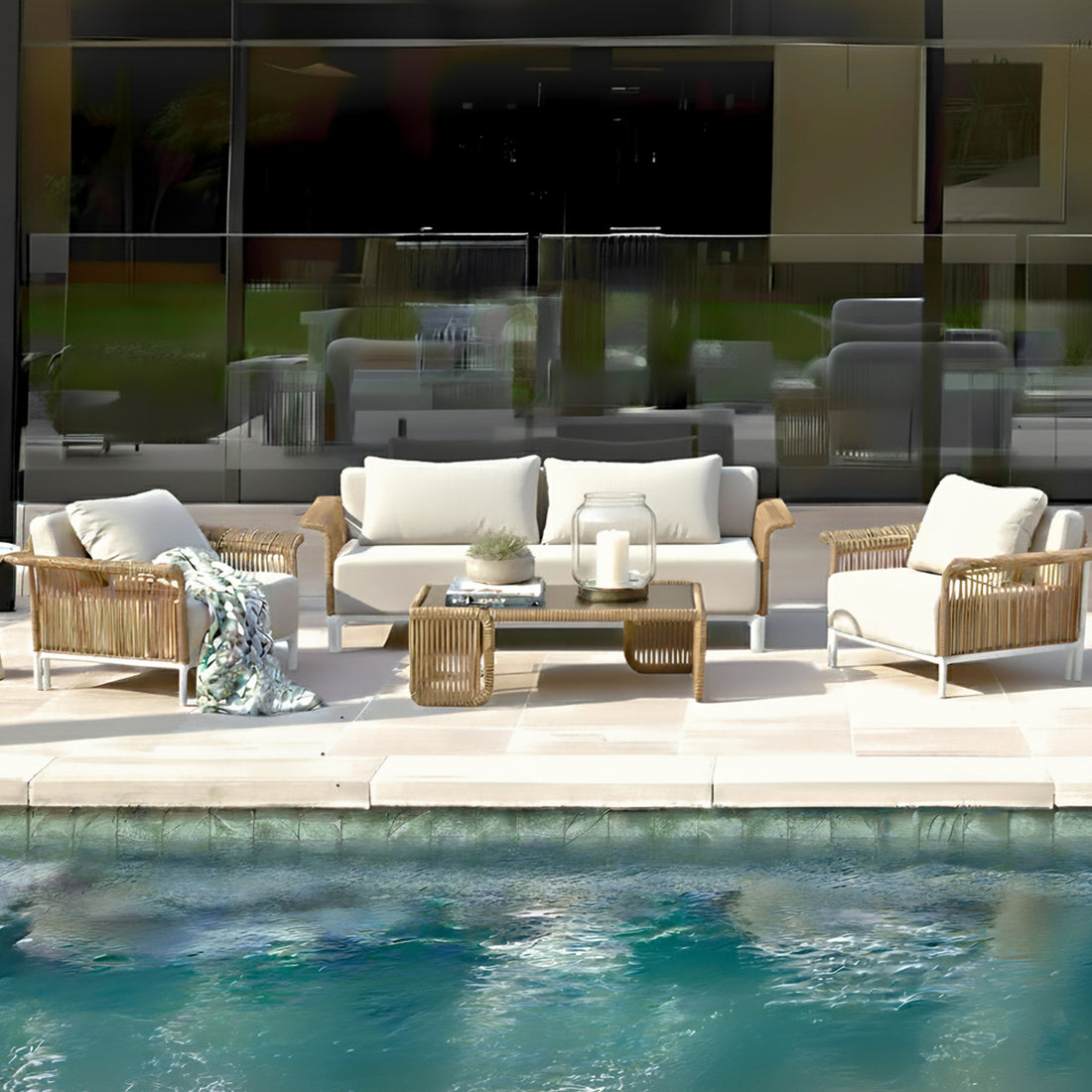 Avon 5-Seater Premium Rattan Outdoor Sofa Set in Cream White features a wicker-style sofa, armchairs with plush cushions, and a coffee table with a glass lantern, creating a resort-like poolside ambiance.