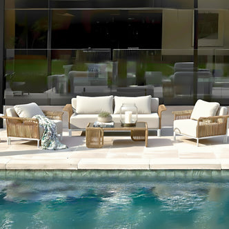 Avon 5-Seater Premium Rattan Outdoor Sofa Set in Cream White features a wicker-style sofa, armchairs with plush cushions, and a coffee table with a glass lantern, creating a resort-like poolside ambiance.