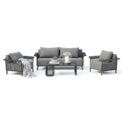 Avon 5 Seater Premium Rattan Outdoor Sofa Set in Grey features charcoal-gray cushioned armchairs, a matching sofa, and a sleek coffee table with books, a succulent, and a candle.