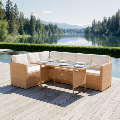Ballena 6 Seater Wicker Outdoor Dining Set in Beige on a wood-plank deck, featuring an L-shaped wicker sofa with off-white cushions and a matching glass-topped table, overlooking a serene lake.