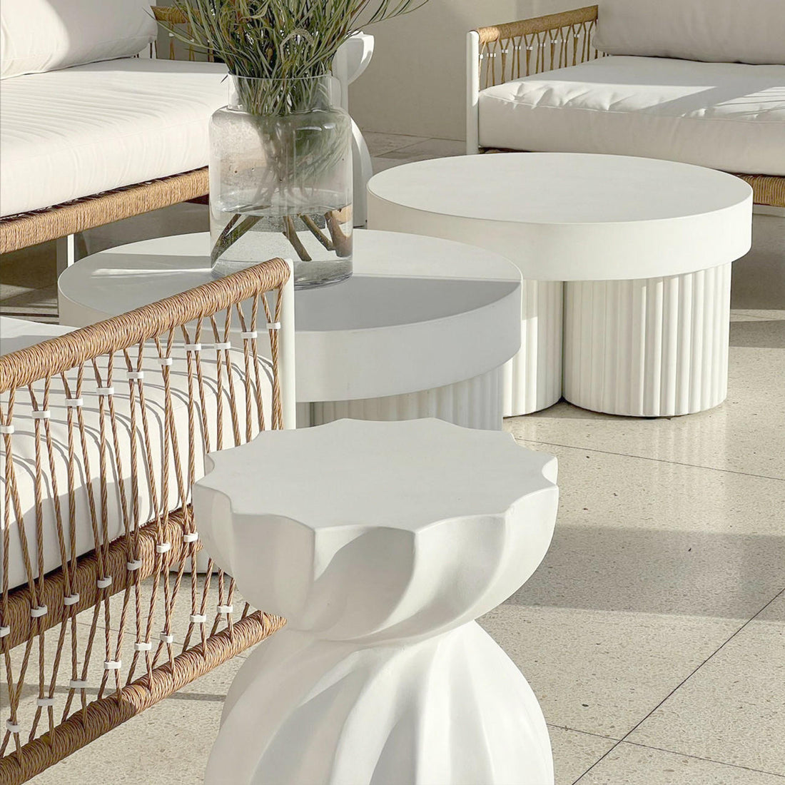 Basalt 70cm Indoor & Outdoor Concrete Coffee Table in White, featuring a sleek, fluted base and minimalist design, perfectly styled with leafy greenery in a glass vase on terrazzo flooring.