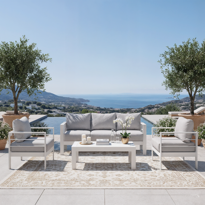 Luxo Bayo 6-Seater Aluminium Outdoor Set in White & Grey, featuring a plush cushioned sofa and armchairs around a low table, elegantly arranged in a scenic outdoor setting with rolling hills and sea views.