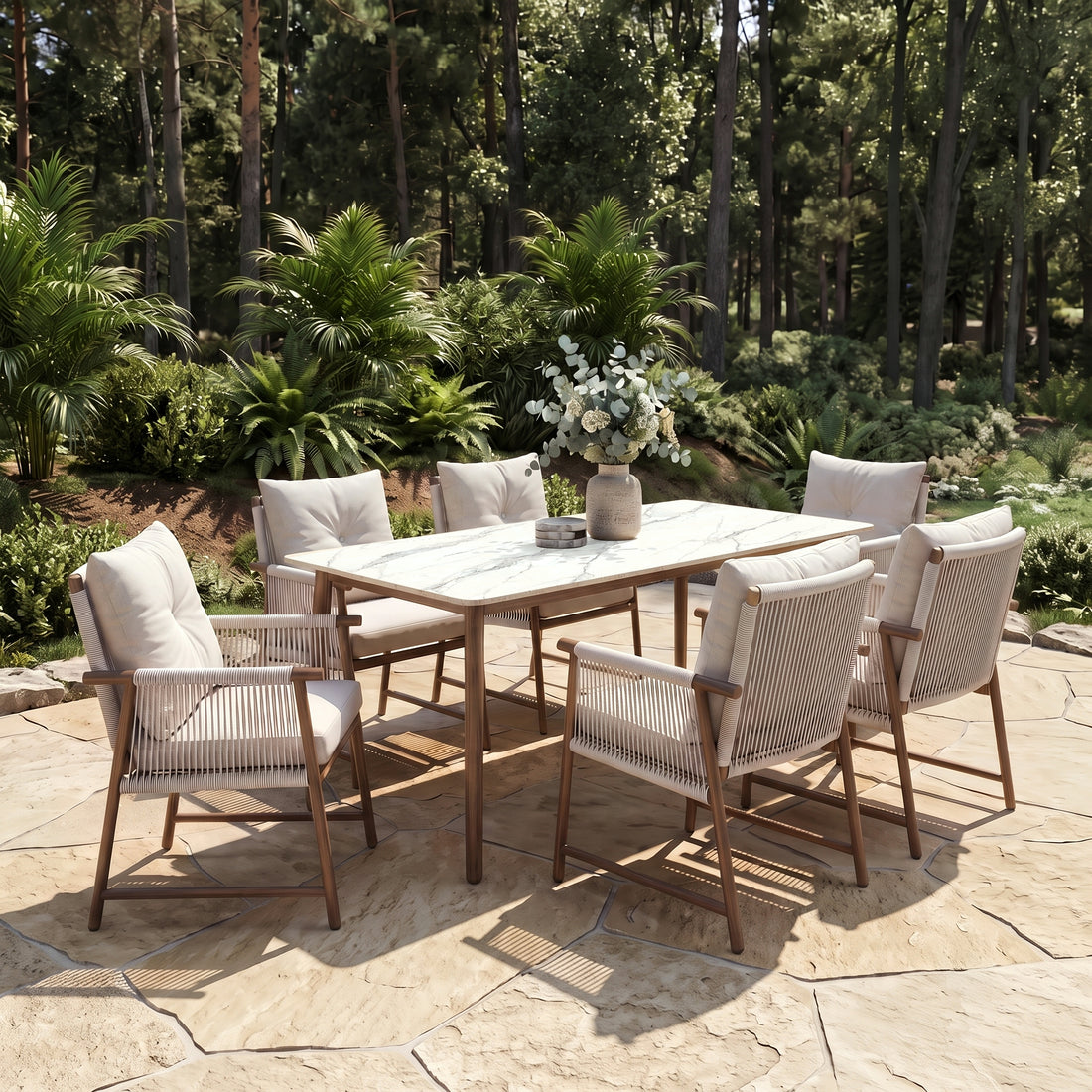 Outdoor dining set with table and chairs on a stone patio surrounded by greenery