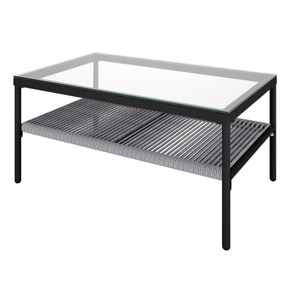 Brujas 4 Seater Wicker Outdoor Lounge Set in Grey features a sleek coffee table with a clear glass top and woven shelf, perfectly complementing the modern lounge ensemble.