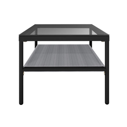 Brujas 4 Seater Wicker Outdoor Lounge Set in Grey features a low, rectangular coffee table with a black metal frame, clear glass tabletop, and gray woven shelf, supported by tubular metal legs.