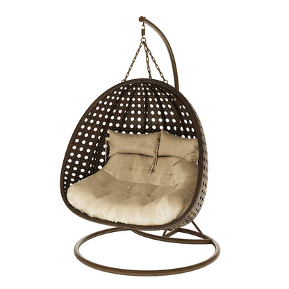 Buena 2 Person Wicker Outdoor Hanging Egg Chair in Brown features a woven rattan-style shell suspended from an arched metal frame, with thick beige cushions for cozy outdoor relaxation.