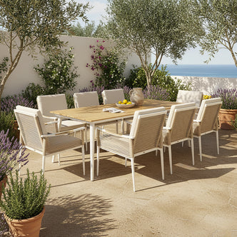 Casara 9 Piece Outdoor Dining Set in White and Beige features a wooden-topped table with slender metal legs, surrounded by eight white-washed wooden chairs with woven backs and cushioned seats, set on a sunlit terrace.