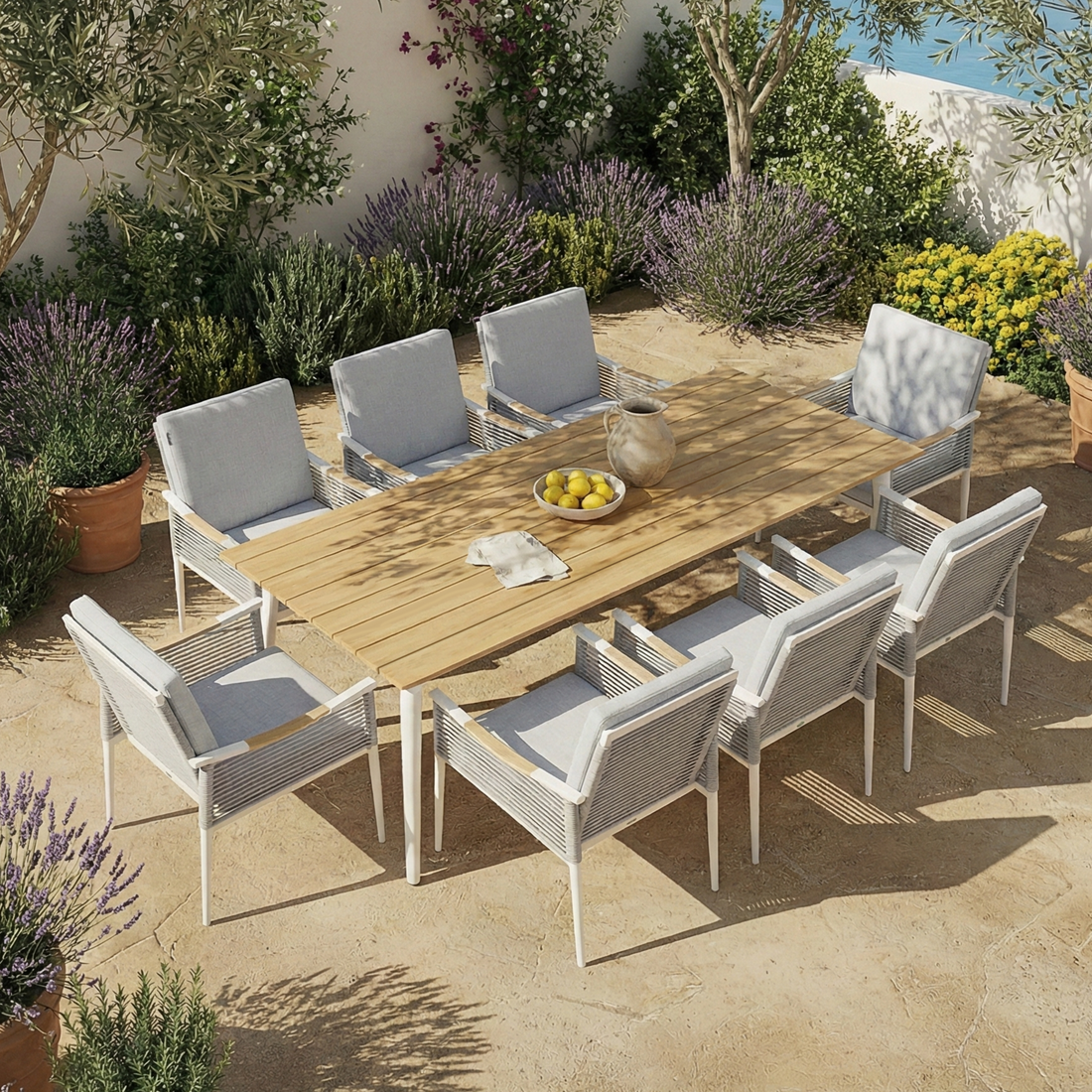 Casara 9 Piece Outdoor Dining Set in White and Grey features a slatted wooden table with eight cushioned armchairs on a sunlit patio, surrounded by Mediterranean greenery and terracotta pots.