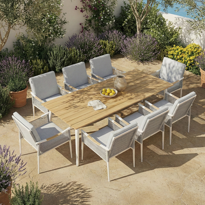 Casara 9 Piece Outdoor Dining Set in White and Grey features a slatted wooden table with eight cushioned armchairs on a sunlit patio, surrounded by Mediterranean greenery and terracotta pots.